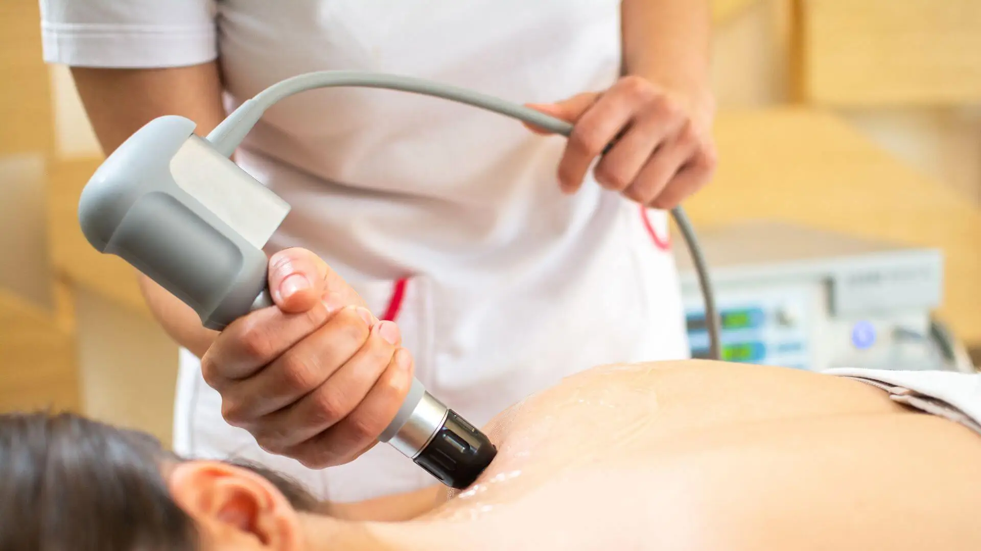 Clinician treating a patient's back with a radial shockwave handpiece